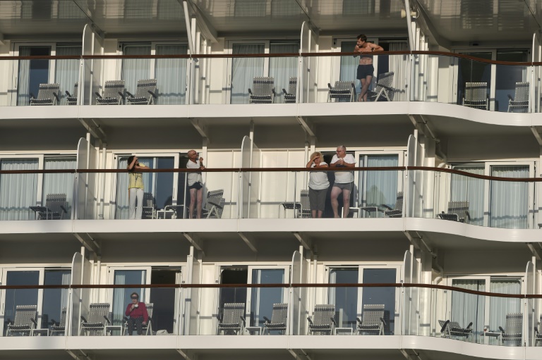Passangers look out from their balconies aboard the Maltese-flagged Mein Schiff 6, operated by German travel giant TUI, at the port of Piraeus. Passangers look out from their balconies aboard the Maltese-flagged Mein Schiff 6, operated by German travel giant TUI, at the port of Piraeus.