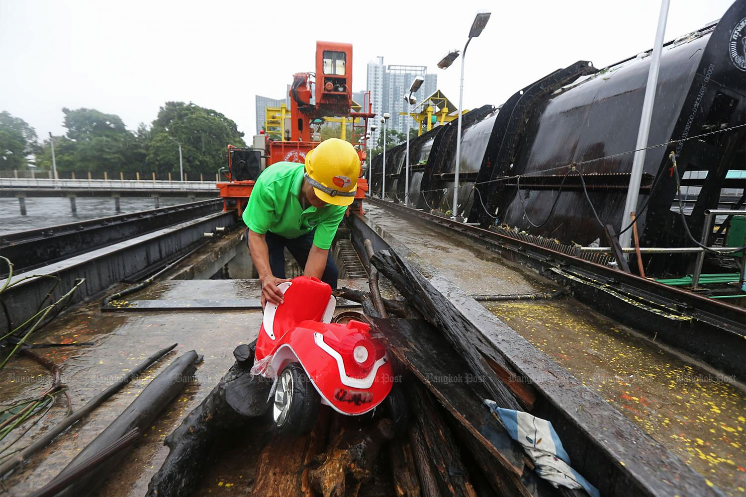 A worker removes an abandoned toy tricycle and other items that jammed the Rama IX water intake station in Bangkok. Every day, staff have to remove large quantities of household rubbish, which block the drains and contribute to widespread flooding in the capital. (Photo by Varuth Hirunyatheb)