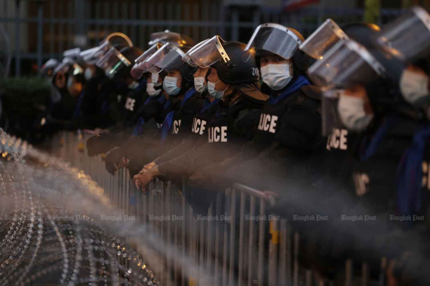 Riot police wait behind razor wire for political demonstrators at Tuek Chai intersection in Bangkok on Wednesday evening, just before the prime minister offered to end the state of severe emergency declared in Bangkok. (Photo: Pornprom Satrabhaya)