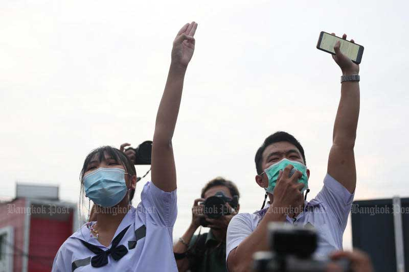 Young anti-government protesters at Kasetsart intersection throw up the three-finger salute on Monday. (Photo by Varuth Hirunyatheb)