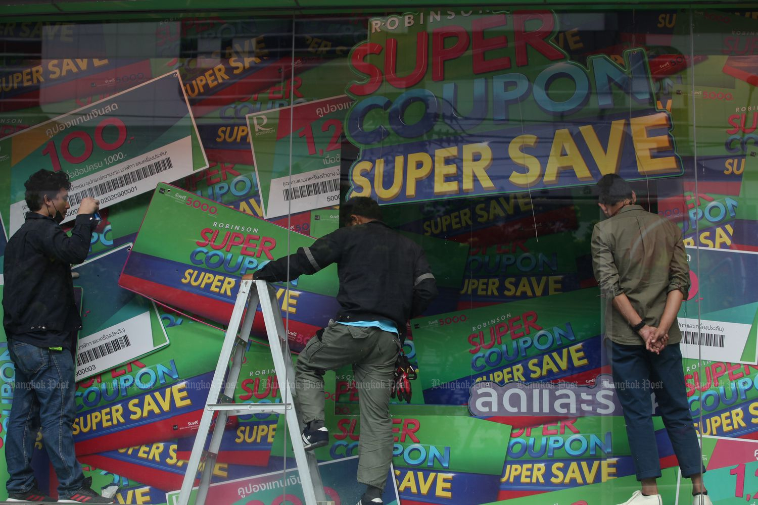 Workers decorate a banner highlighting the ‘Super Coupon Super Save’ promotion at the Robinson Department Store on Rama IV Road on Oct 2. (Photo by Apichart Jinakul) Workers decorate a banner highlighting the ‘Super Coupon Super Save’ promotion at the Robinson Department Store on Rama IV Road on Oct 2. (Photo by Apichart Jinakul)