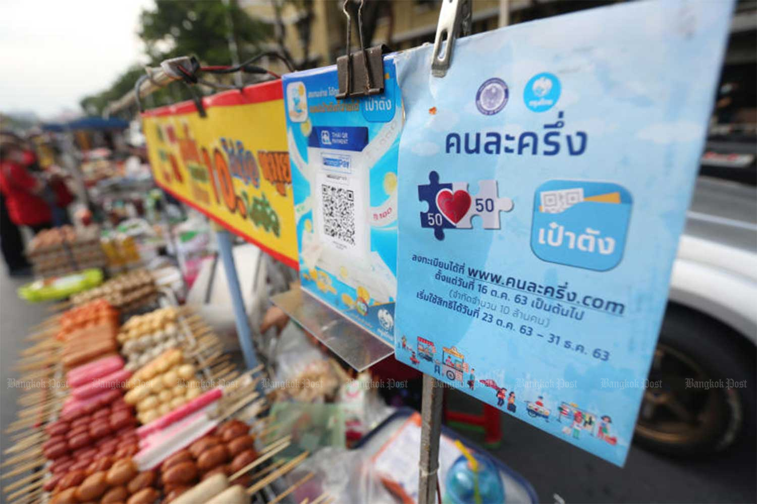 A vendor selling grilled hotdogs, sausages and fishballs displays a placard from the government's co-payment scheme during a demonstration at Democracy Monument on Nov 8. (Photo by Varuth Hirunyatheb)