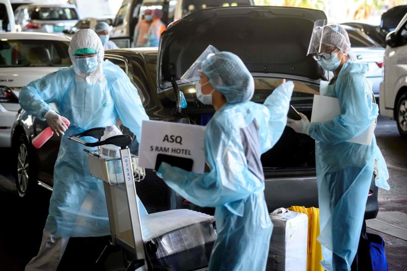 FILE PHOTO: An employee (left) wearing personal protective equipment (PPE) disinfects the luggage of arriving international flight passengers before their transfer to a hotel for the compulsory 14-day Alternative State Quarantine (ASQ), to prevent the spread of the Covid-19 coronavirus, at Suvarnabhumi Airport in Samut Prakan province on Nov 16, 2020. (AFP)