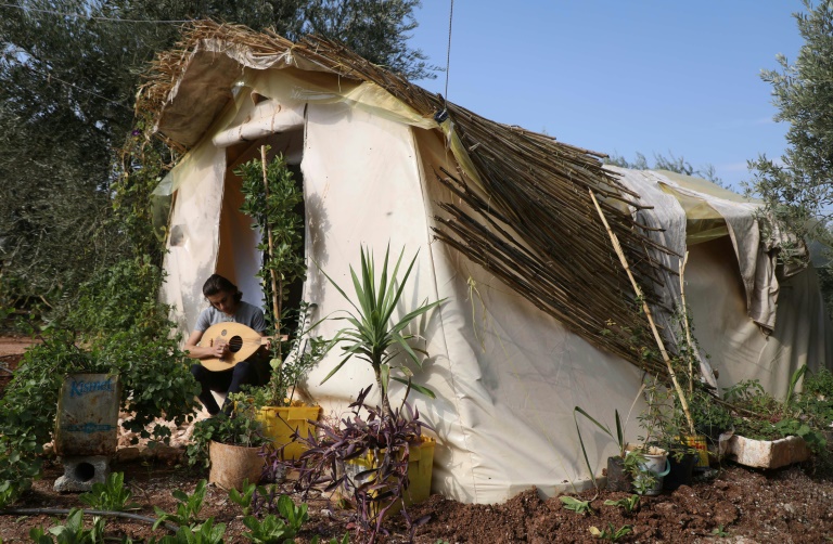 Displaced Syrian teenager Wissam Diab plays the oud at his new home, a tent surrounded by plants Displaced Syrian teenager Wissam Diab plays the oud at his new home, a tent surrounded by plants
