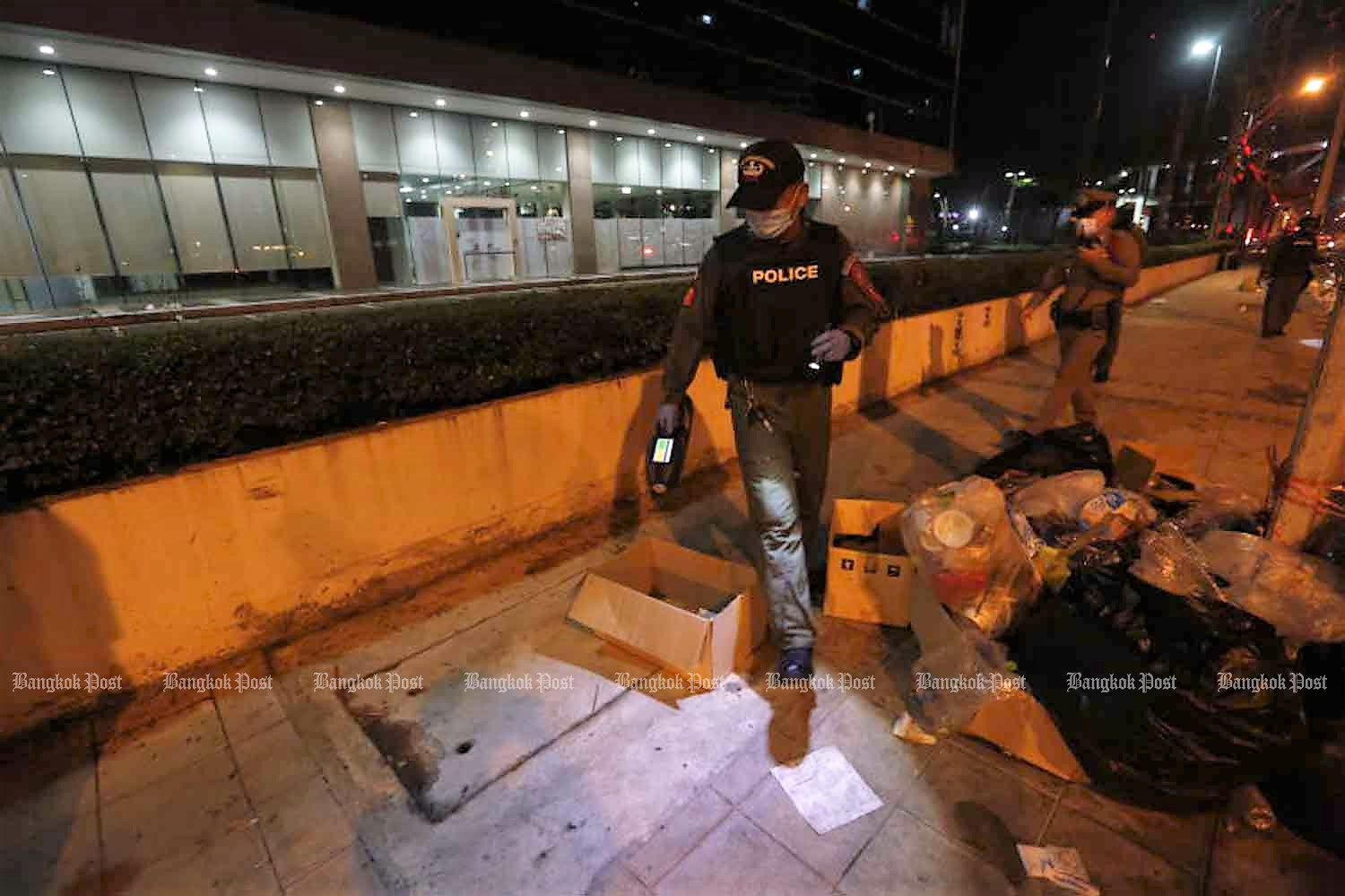 Police examine the protest site outside Siam Commercial Bank headquarters, across from the area where the shooting occurred, in Chatuchak district, Bangkok, after the rally ended on Wednesday night. (Photo: Arnun Chonmahatrakool)