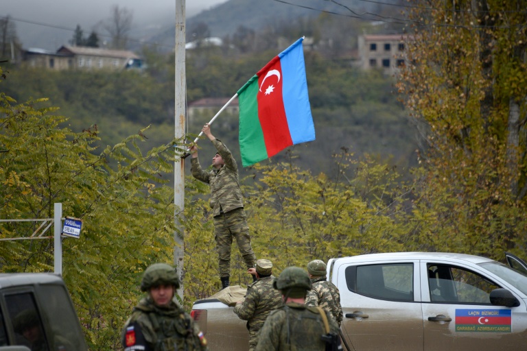 An Azerbaijani soldier fixes a national flag on a lamp post in the town of Lachin. An Azerbaijani soldier fixes a national flag on a lamp post in the town of Lachin.
