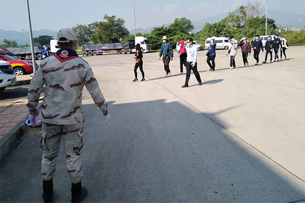 A security official watches 10 Thais returning from Tachilek to Mae Sai district of Chiang Rai through the checkpoint at the second Thai-Myanmar Friendship Bridge on Monday. (Photo: Mai Sai district office Facebook) A security official watches 10 Thais returning from Tachilek to Mae Sai district of Chiang Rai through the checkpoint at the second Thai-Myanmar Friendship Bridge on Monday. (Photo: Mai Sai district office Facebook)