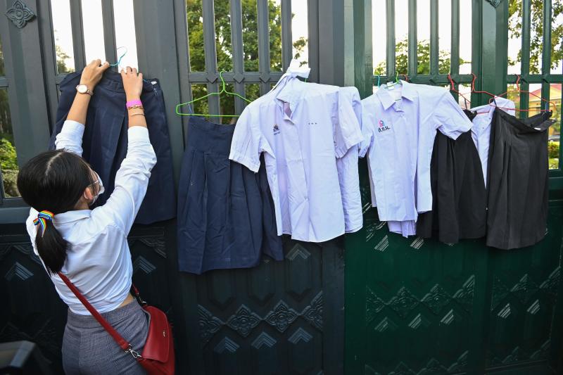 A protester hangs up school uniforms on the gate of the Ministry of Education during a "Bad Student" rally in Bangkok on Dec 1, 2020. (AFP file photo)