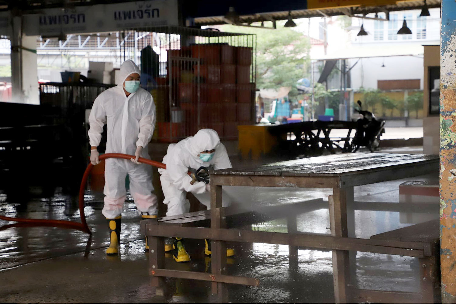 Workers spray disinfectant at the shrimp market in Samut Sakhon on Friday, as authorities try to contain the spread of coronavirus first detected in a shrimp vendor. (Photo from Samut Sakhon Public Relations Office Facebook page)