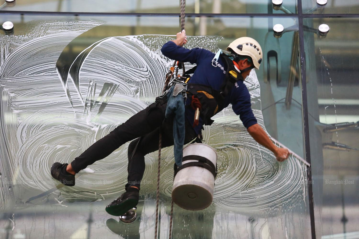 A worker wipes clean glass windows at a four-storey terminal at Suvarnabhumi airport. (Photo by Somchai Poomlard)