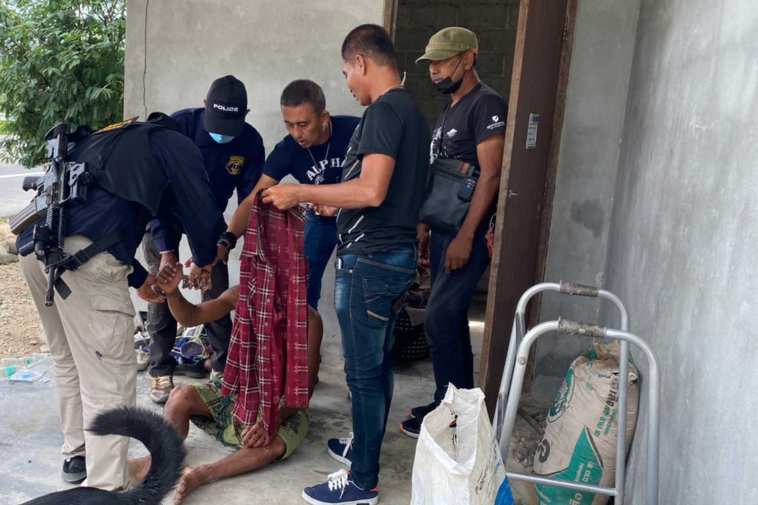 A man, 38, sits on the floor as officials arrest him at his house in Nakhon Si Thammarat for allegedly raping his daughter and taking drugs. (Photo by Nujaree Raekrun)