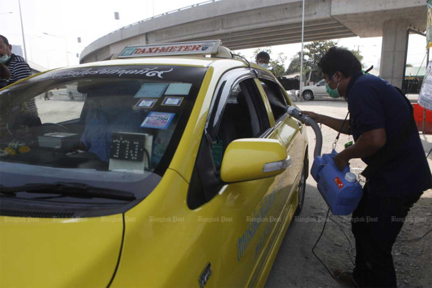 An official sprays disinfectant inside a taxi at Mor Chit bus terminal in Bangkok on Tuesday to boost confidence among passengers using the service. (Photo by Nutthawat Wicheanbut)