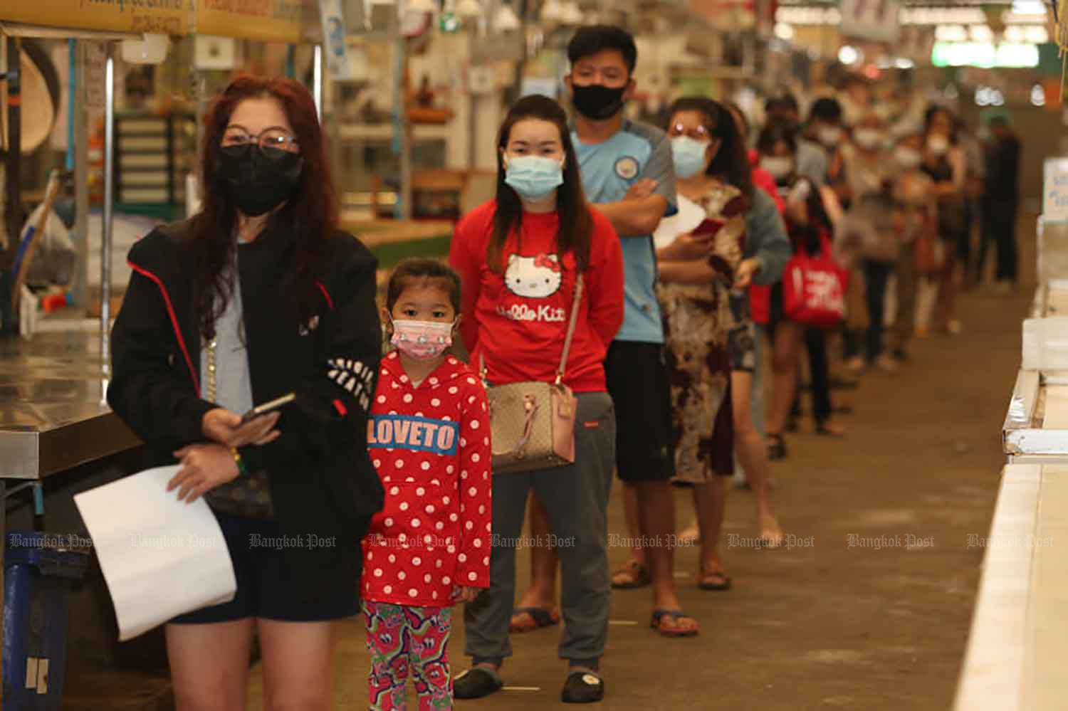 Vendors from Thanom Mitr wet market in Bangkok's Bang Khen district queue for Covid-19 tests provided by City Hall. Its public health service office has shut the market for three days, until Thursday, after a vendor there tested positive for the coronavirus.  (Photo by Varuth Hirunyatheb)