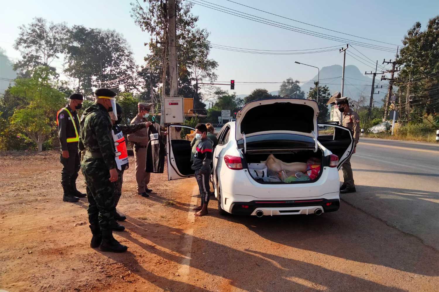 Officers search a Toyota Yaris driven by a woman and find four illegal Myanmar migrants,  at a road checkpoint in Thong Pha Phum district, Kanchanaburi, on Friday. (Photo:  Piyarat Chongcharoen)