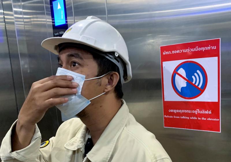 A worker adjusts his face mask as a preventive measure against the Covid-19 coronavirus inside an elevator with a restriction notice in Bangkok on Jan 18, 2021. (AFP file photo)