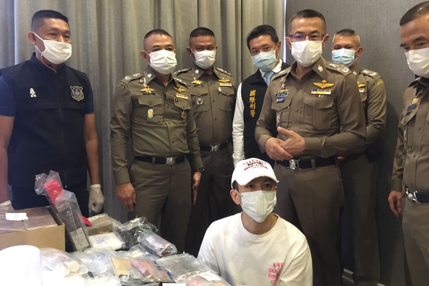 Police arrest Chou Yi Shen (seated) at a condominium in Ratchathewi district in Bangkok on Monday. (Royal Thai Police photo)