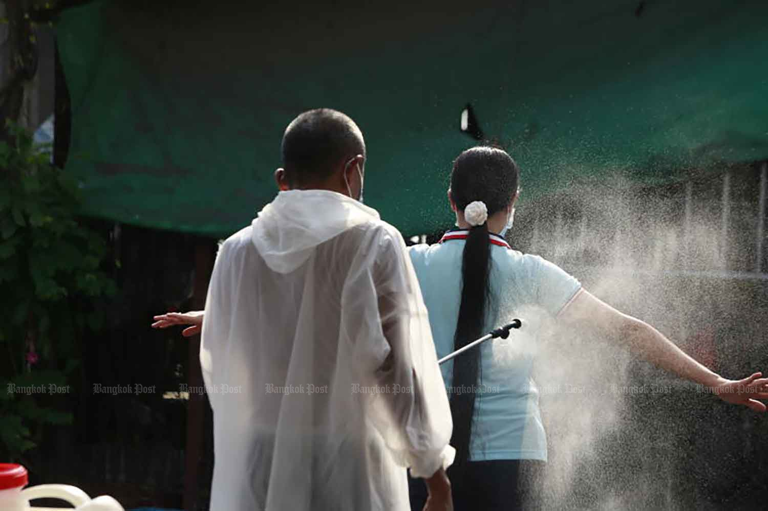 A disease control worker sprays disinfectant on a migrant worker at a field hospital in Samut Sakhon province on Jan 10. ARNUN CHONMAHATRAKOOL