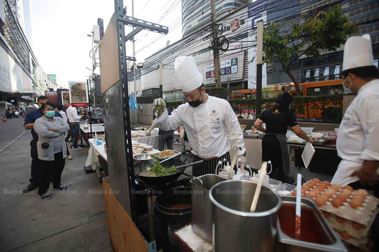 With most hotels empty of guests, chefs from the Grand Mercure Hotel on Ratchadaphisek Road were out on the street preparing food for sale to passers-by, in Bangkok on Friday. (Photo: Nutthawat Wicheanbut)