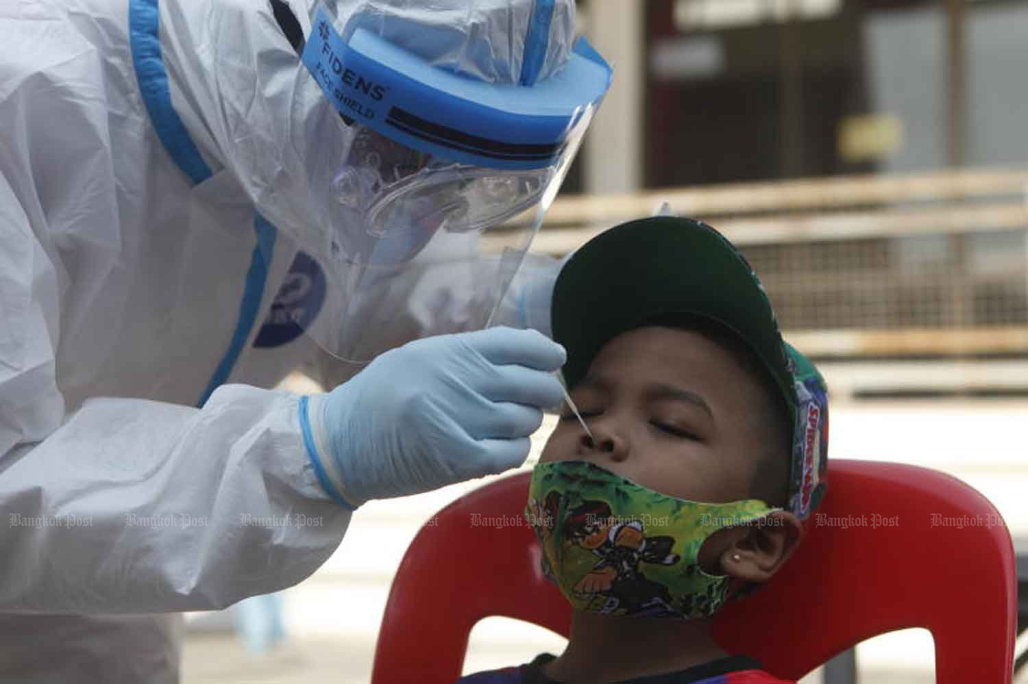 A disease control worker collects a nasal swab from a boy during active Covid-19 case finding in Phasicharoen district, Bangkok, last Thursday. (Photo: Nutthawat Wicheanbut)