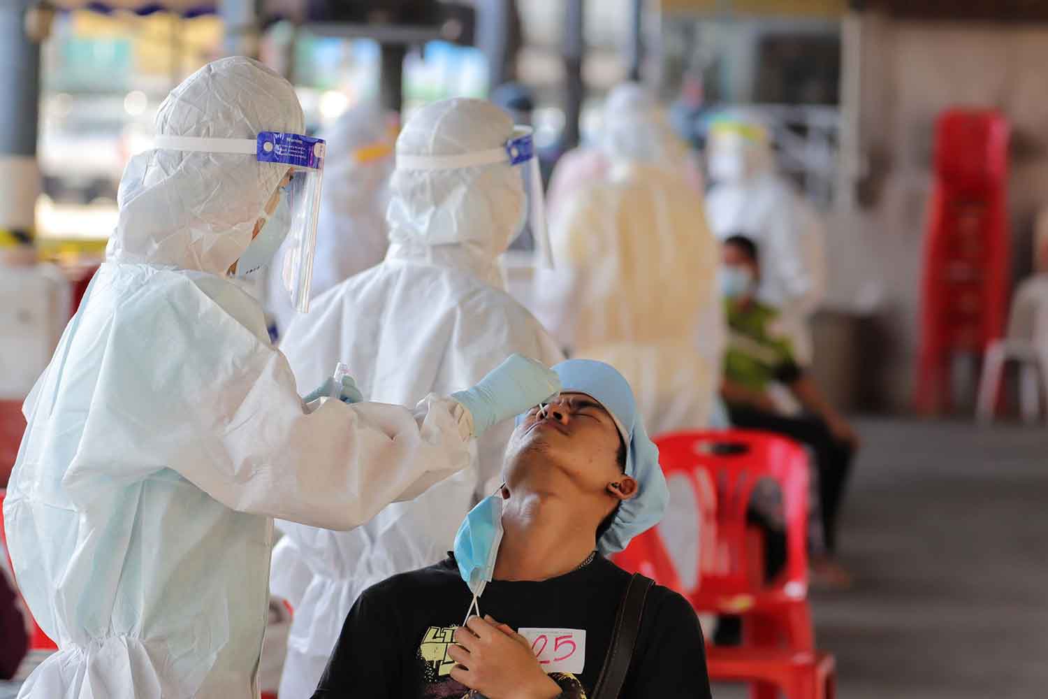 Health workers collect nasal swabs for Covid-19 tests at Pornpat market in Thanyaburi district, Pathum Thani, on Friday, after 60 new Covid-19 cases were reported in the district on Thursday. (Photo: Pongpat Wongyala)