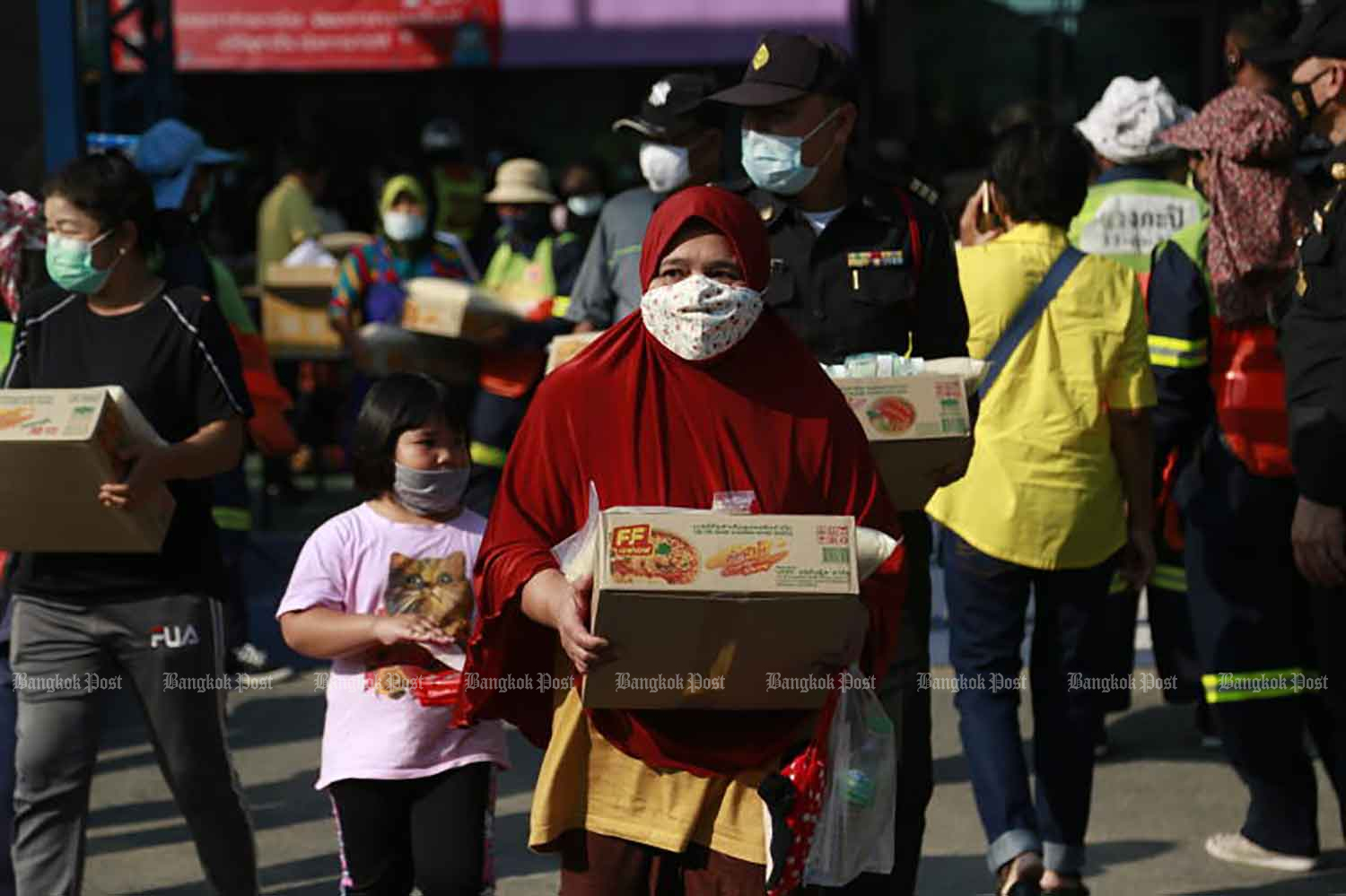 People receive food handouts in the wake of the Covid-19 pandemic at Wang Som community in Bang Kapi district, Bangkok, on Wednesday when the country confirmed 72 new Covid-19 cases. (Photo by Arnun Chonmahatrakool)