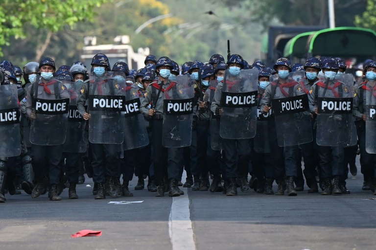 Police march on a road to clear away protesters from holding a demonstration against the military coup in Yangon.