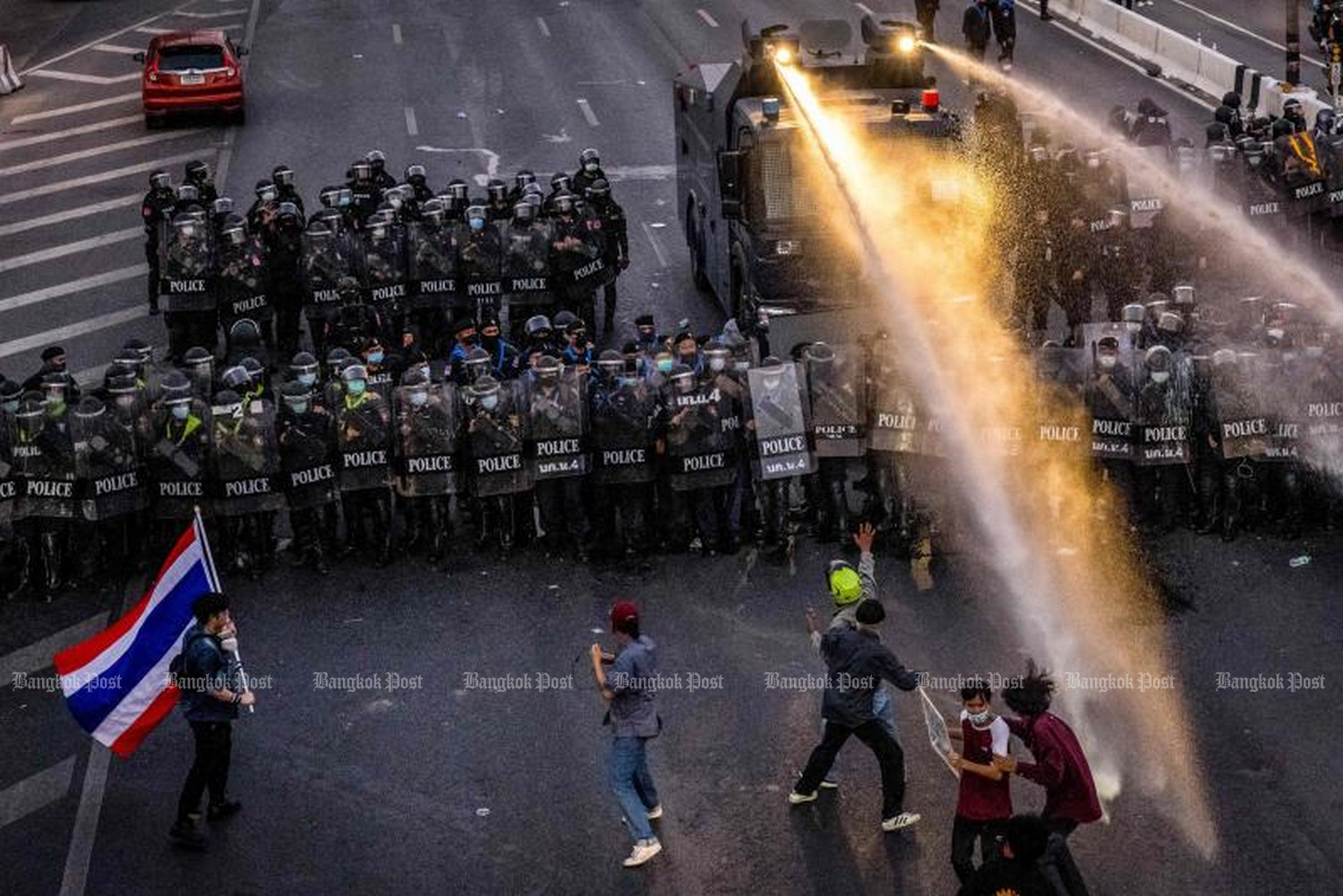 Police use a water cannon against pro-democracy protesters marching toward the residence of Prime Minister Prayut Chan-O-Cha, on Vibhavadi-Rangsit Road in Bangkok, early on Sunday night. (Photo: AFP)