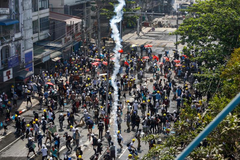 Protesters run as tear gas is fired during a demonstration against the military coup in Yangon on Monday. (AFP photo)