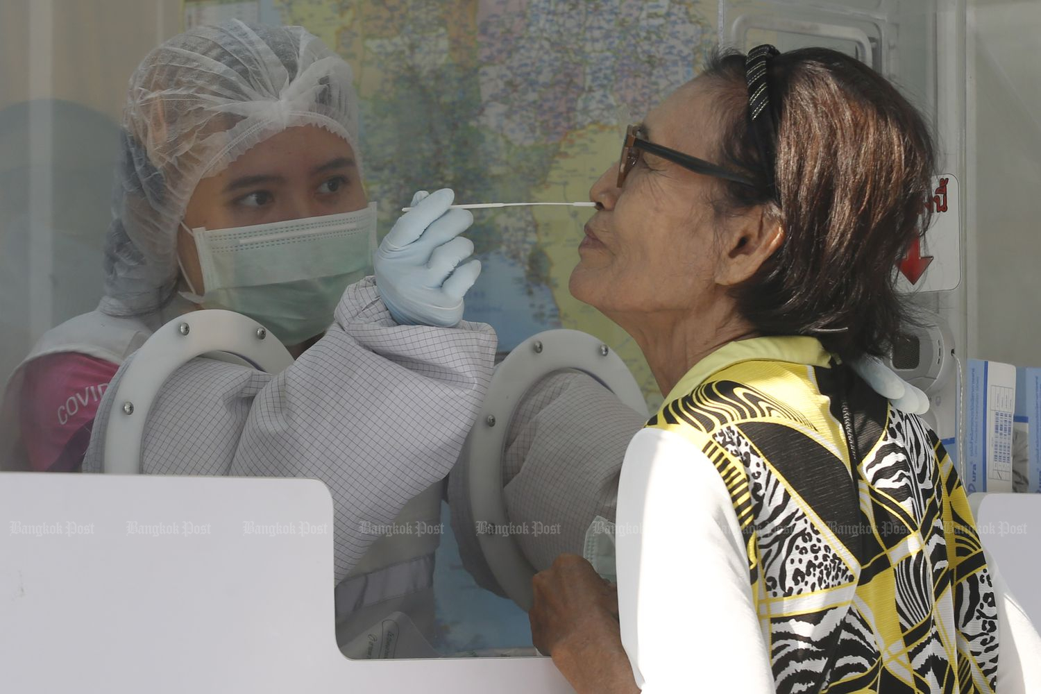 A health employee takes a nasal swab of a woman at Charoen Dhammaram temple in Sai Mai district, Bangkok, on Friday. Free Covid-19 tests were available for monks and people in nearby communities there. (Photo by Apichit Jinakul)