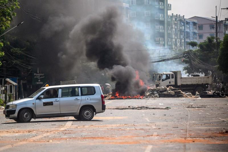 Soldiers set on fire barricades, which had been erected by protesters demonstrating against the military coup, in attempt to clear the road of obstructions in Yangon on Friday. (AFP photo)