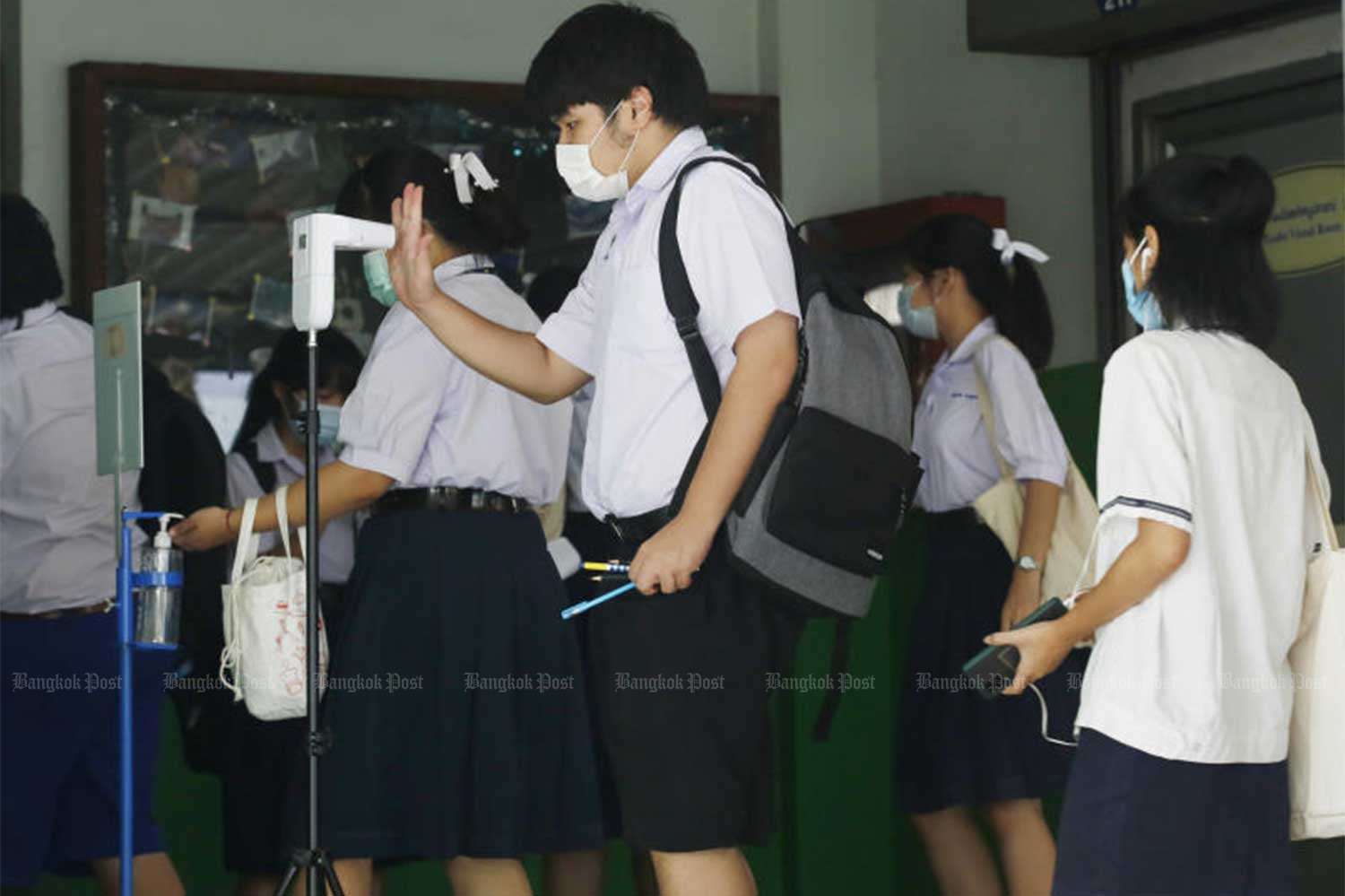 Students, all wearing face masks, enter the Covid-screening point at a building of Donmuang Taharnagardbamrung School in Bangkok for the General Aptitude Test (GAT)/ Professional and Academic Aptitude Test (PAT) for Grade 12 students on Saturday. (Photo by Apichit Jinakul)