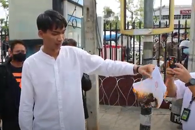 Vachiravich Thetsrimuang burns his summons before entering the Muang district police station in Khon Kaen on Monday on charges arising from protests in Khon Kaen on Feb 12, Feb 20 and March 1. (Photo: Chakkrpan Natanri)