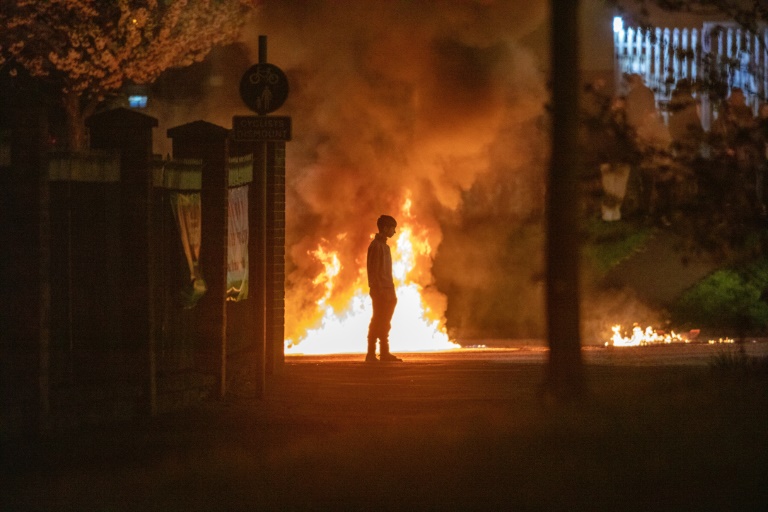 A person stands in front of the flames in Newtownabbey, Befast on April 3, during a week of rioting A person stands in front of the flames in Newtownabbey, Befast on April 3, during a week of rioting