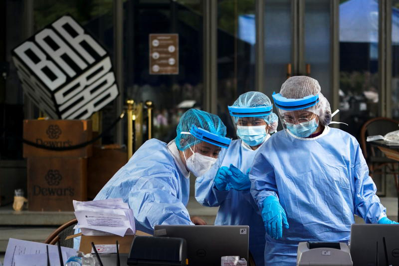 Healthcare workers work in front of a closed bar and take nasal swab samples from a local resident for a Covid-19 test on Thursday after hundreds of residents in the trendy Thong Lor neighborhood tested positive for the coronavirus. (Reuters photo)