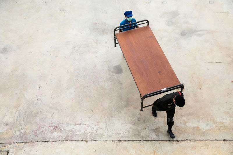 A member of the military and a worker carry a bed frame at a Covid-19 field facility at Ratchaphiphat Hospital in Bangkok on Saturday. (Bloomberg photo)