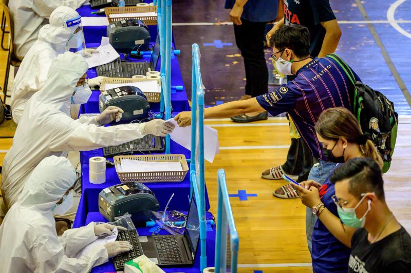 Medical workers wearing PPE (personal protective equipment) register people during a mass testing event at a sports complex in Bangkok on Saturday. (AFP photo)