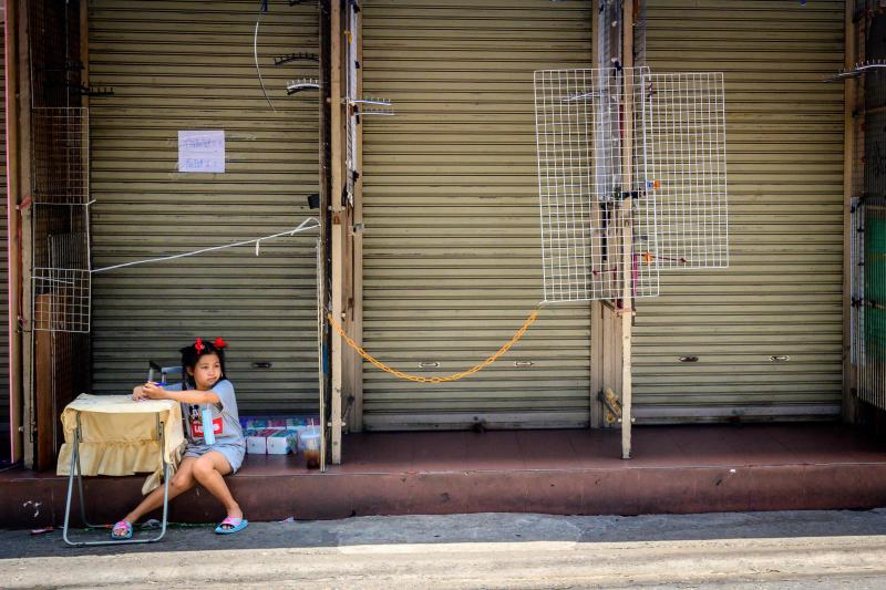 A child sits at a table in front of closed shops at Pratunam market in Bangkok on April 16, 2021, as Thailand imposes further restrictions to deal with a spike in the number of Covid-19 coronavirus cases. (AFP photo)