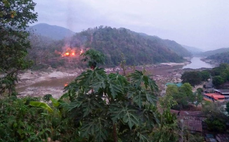 This handout from Kawthoolei Today taken and released on April 27, 2021 shows fires burning at a Myanmar military base along the bank of the Salween river, as seen from Mae Sam Laep town in Thailand's Mae Hong Son province, after the base was attacked and captured by the Karen National Union (KNU) as the country remains in turmoil after the Feb 1 military coup. (Photo by Handout / KAWTHOOLEI TODAY / AFP)