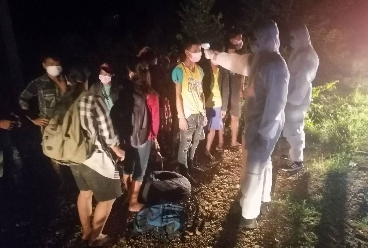 Soldiers in PPE suits check the temperatures of Myanmar border crossers caught in Muang district, Kanchanaburi on Wednesday night. (Photo: Piyarat Chongcharoen) Soldiers in PPE suits check the temperatures of Myanmar border crossers caught in Muang district, Kanchanaburi on Wednesday night. (Photo: Piyarat Chongcharoen)