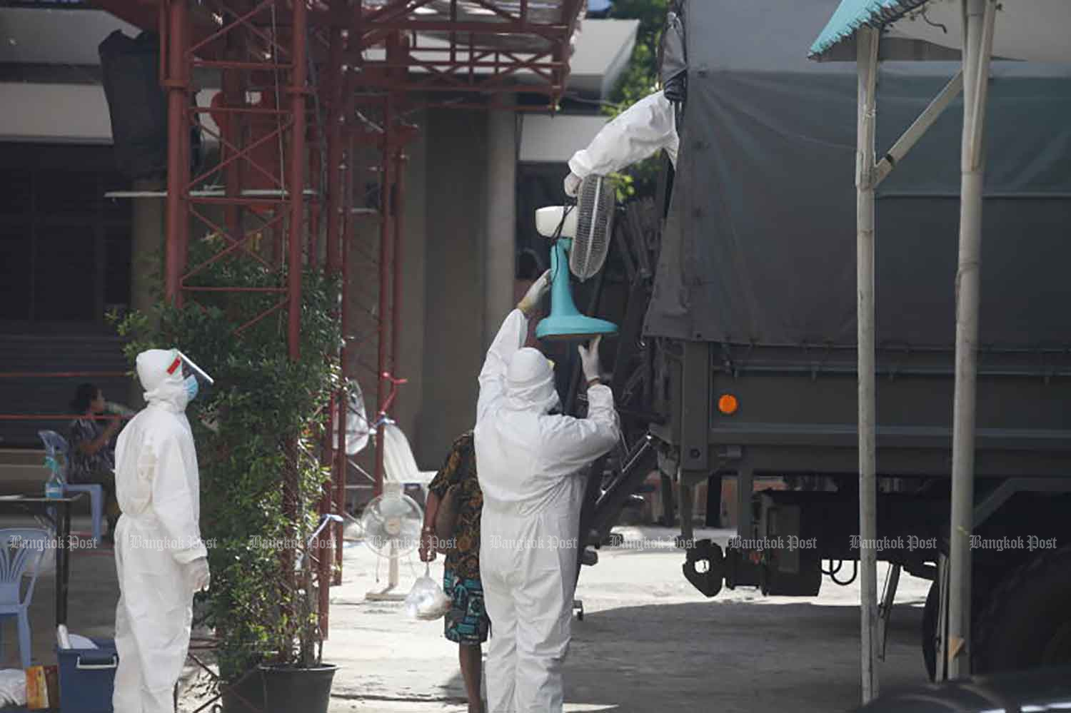 Disease control workers are transporting Covid patients and their belongings from Klong Toey slum community in Bangkok to a field hospital on Thursday. (Photo: Nutthawat Wicheanbut)