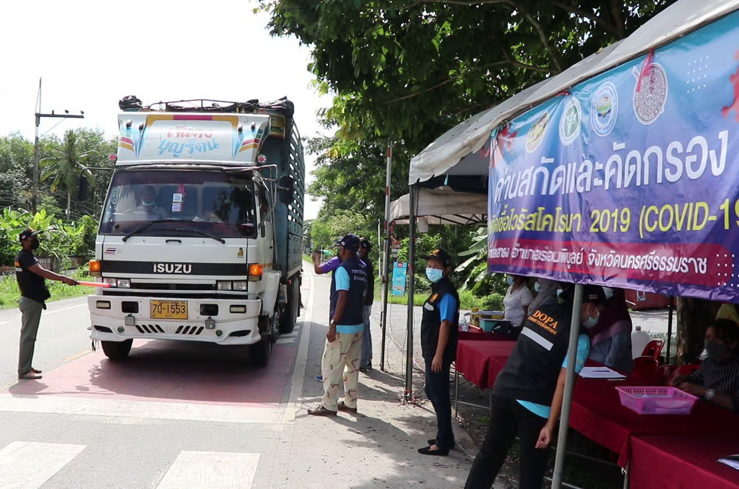 Officials at a Covid-19 screening checkpoint in tambon Sao Thong of Ron Phibun district on Friday stop a truck to inspect the people on board. (Photo: Nujaree Rakrun)