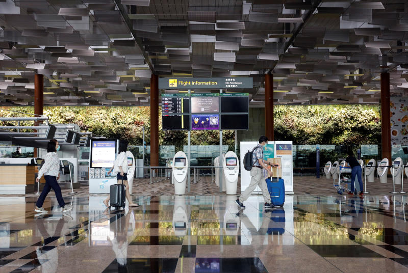 FILE PHOTO: People wearing protective face masks walk past self check-in machines, amid the spread of the coronavirus disease (Covid-19) at Changi Airport in Singapore Oct 12, 2020. (Reuters)