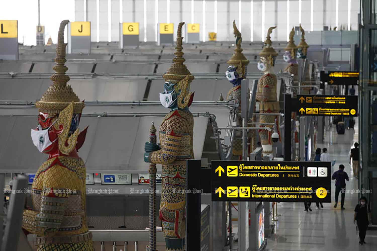 'Yaksa' statues at Suvarnabhumi airport are adorned with face masks to remind the public to remain vigilant during the Covid-19 pandemic. (Photo: Varuth Hirunyatheb)