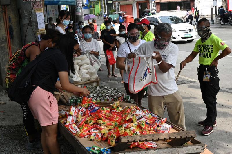 FILE PHOTO: Local residents collect free food packets from a food bank called a "community pantry", run by volunteers, along a road in Quezon City in suburban Manila, April 21, 2021. (AFP)