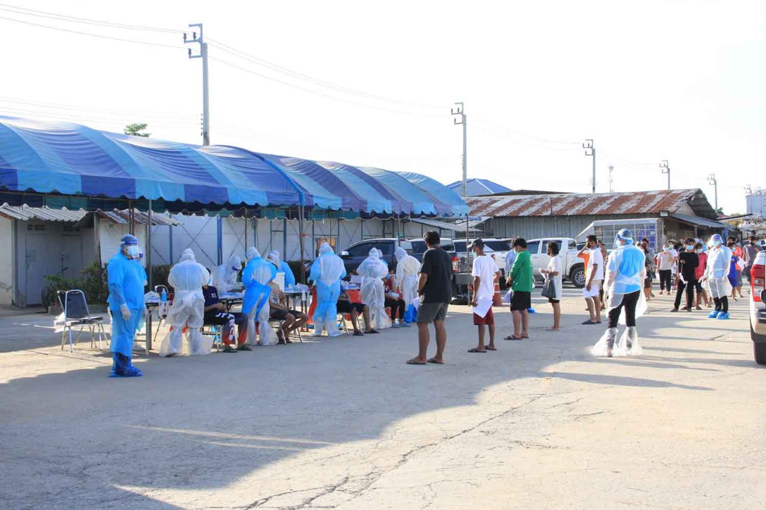 Workers queue for Covid-19 tests at a concrete pipe factory in tambon Praeksa of Muang district, Samut Prakan, on Wednesday. More than 100 of about 300 workers there tested positive for the disease. (Photo: Sutthiwit Chayutworakan)