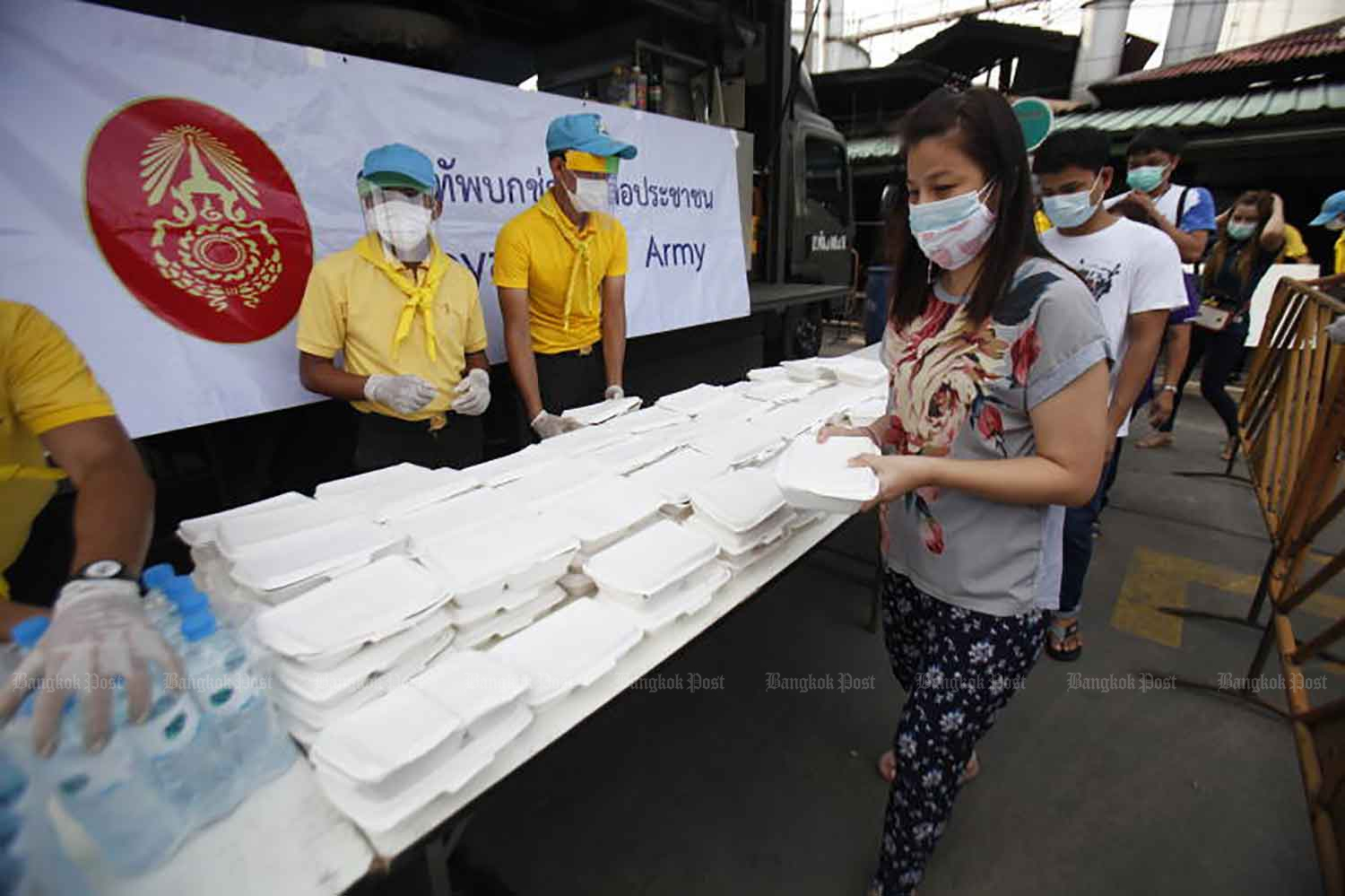 People in Klong Toey district of Bangkok receive free meals and drinking water from the army, which will provide the service to help relieve hardship during the Covid-19 outbreak at Wat Klong Toey Nai until next Tuesday. (Photo: Nutthawat Wicheanbut)