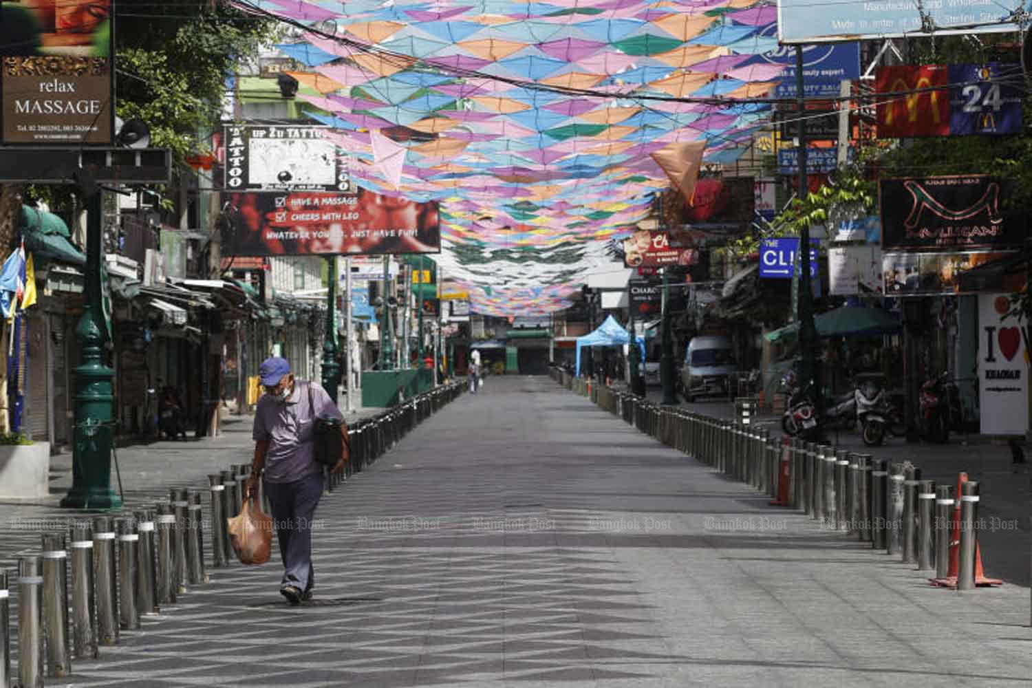 A lone man walks along a deserted street in normally bustling Khao San Bangkok on Sunday. The third wave of Covid-19 has led to strict controls that have brought tourism in the area to a halt. (Photo: Apichit Jinakul)