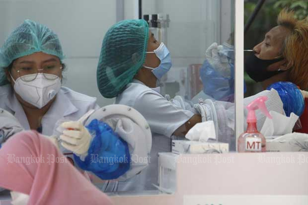 Medical workers take nasal swabs from people who arrive for a Covid-19 test at the Bansomdejchaopraya Rajabhat Institute in Bangkok.