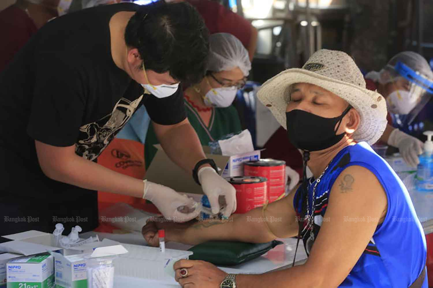 Health workers take blood samples for testing for Covid-19 at Klong Toey market in Bangkok on Thursday. (Photo: Pornprom Satrabhaya)