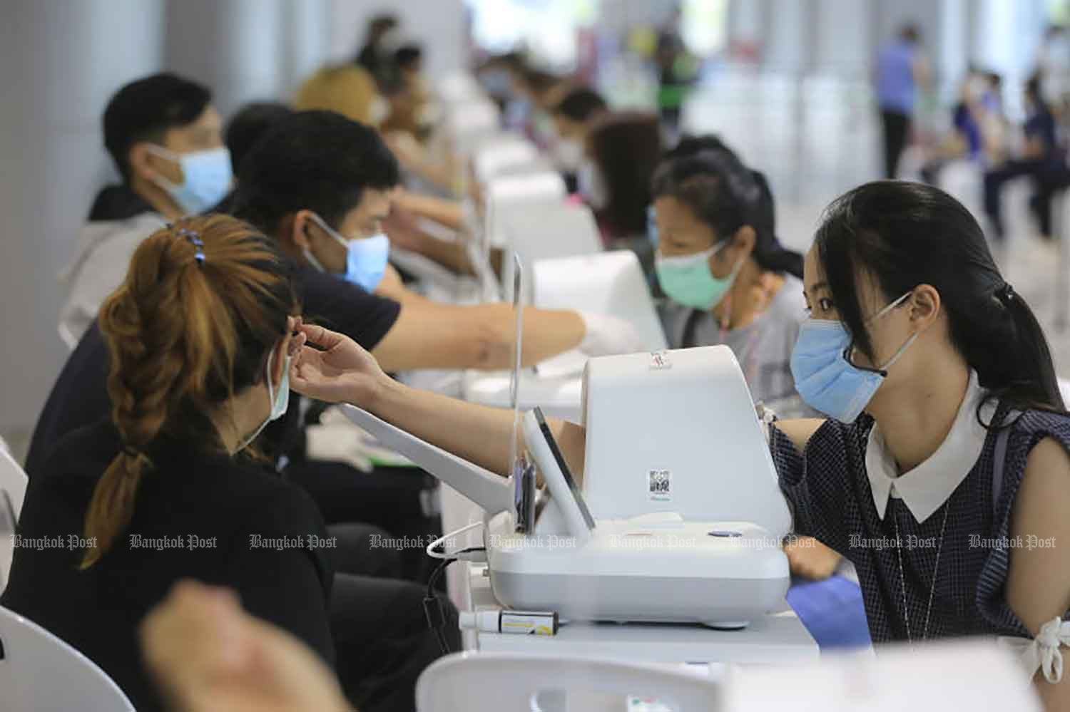 Educational personnel have their blood pressures measured before being inoculated against Covid-19 at the Bang Sue Grand Station in Bangkok on Thursday. (Photo: Pornprom Satrabhaya)